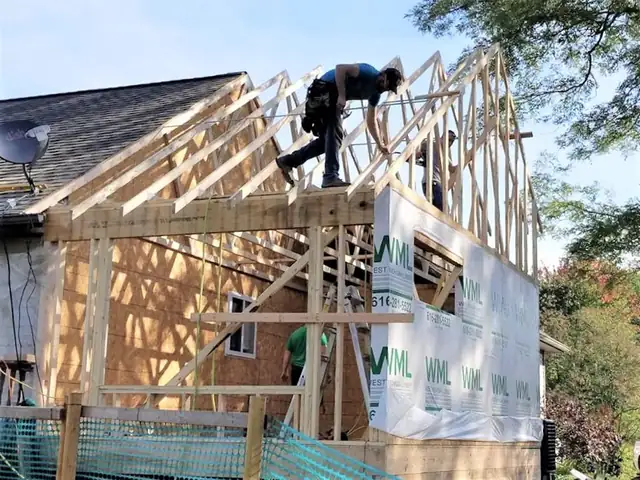 Home addition under construction in West Michigan with new roof framing and white weather barrier