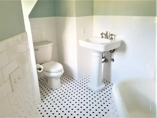 Vintage-style bathroom with white subway tile walls, mint green upper walls, black and white penny tile floor and a pedestal sink