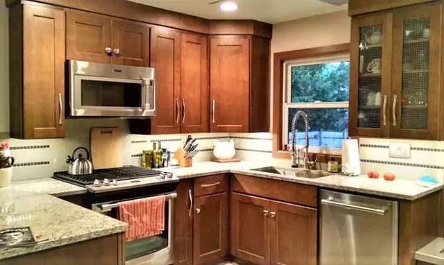 Cherry wood kitchen with granite countertops, gas range, glass-front cabinets and a window over the sink