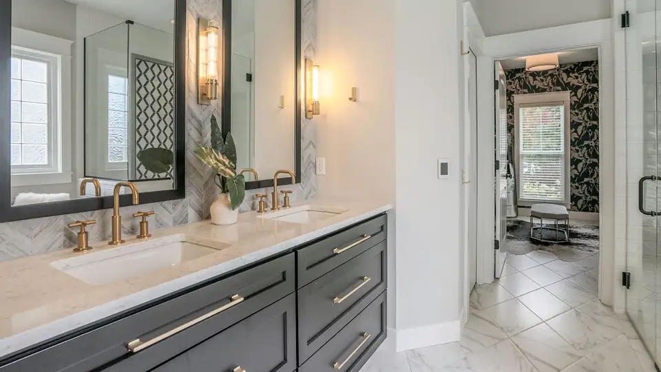 Bathroom remodeling Grand Rapids area: master bath with dark double vanity, marble countertop, gold faucets and black-framed mirrors