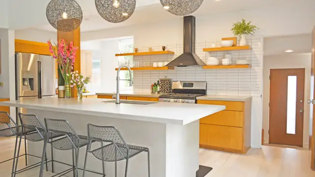 Modern kitchen with a white quartz waterfall island, wood cabinetry, open wood shelving and white subway tile
