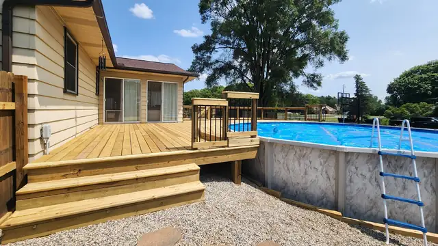 Wood deck with steps and metal railing built beside an above-ground pool at a West Michigan home